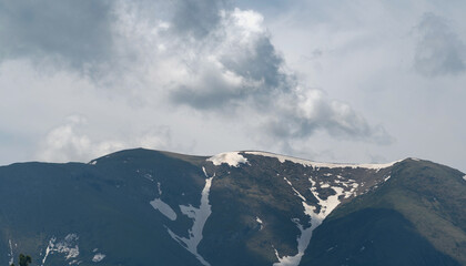Snow-capped mountain peaks beneath a cloudy sky.