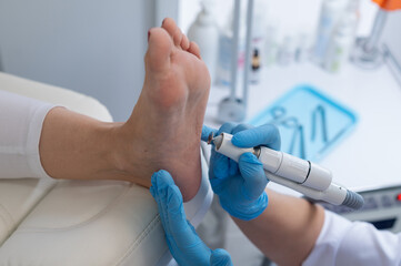 The podologist treats the feet using electric device machine. Patient on medical pedicure...