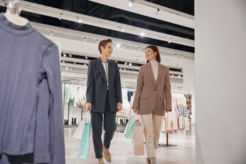Young woman friends enjoying shopping together in big fashion shop mall
