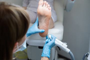 The podologist treats the feet using electric device machine. Patient on medical pedicure...