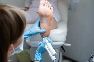 The podologist treats the feet using electric device machine. Patient on medical pedicure...