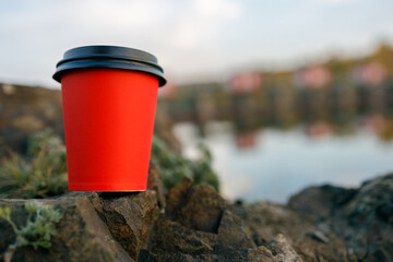 a red disposable glass for hot drinks on the edge of a stone cliff