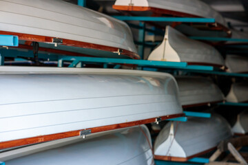 A row of white and brown kayaks are stacked on top of each other