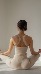 An unrecognizable woman practicing yoga in a minimalist room with soft lighting at sunrise