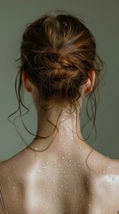 Close-up of a unrecognizable woman's back and neck with wet hair against a neutral background