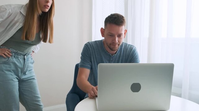 Shocked woman caught her man watching pornography video and cheating with mistress on laptop at home. Wife shouting on husband, while he ashamed and close computer. Couple quarrel. Family conflict 