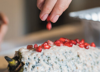 Preparation of the famous chiles en Nogada, traditional Mexican food in the month of September, stuffed chile being covered by the nogada which is a cream with walnut and hand adding pomegranate.