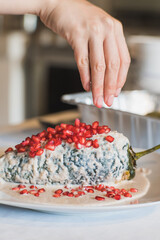 Preparation of the famous chiles en Nogada, traditional Mexican food in the month of September, stuffed chile being covered by the nogada which is a cream with walnut and hand adding pomegranate.