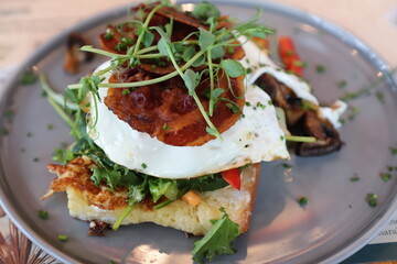 French toast with pancetta, egg, rocket on a gray plate