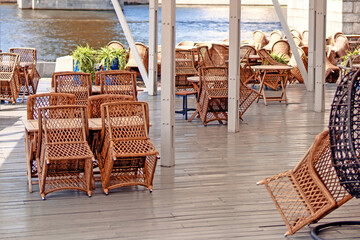 quaint street cafe showcases woven furniture stacked for cleaning, embodying a serene pause before...