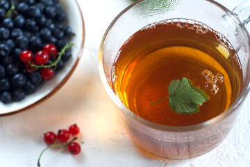 Black tea in a mug on the table, next to it a saucer with blueberries and lingonberries