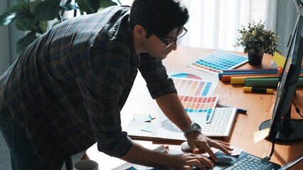 Professional designer looking and designing logo graphic at meeting. Closeup of business man working on colored palettes and writing idea on sticky notes on table with equipment and paper. Symposium.