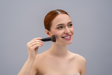 Young pretty woman doing make up and using face brush