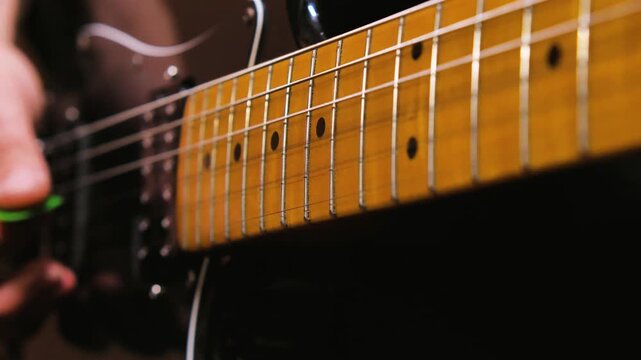 Close-up of a man's hands playing an electric guitar. Focus on fingers running on the strings performing a solo. Honing the skills of playing guitar in a home studio