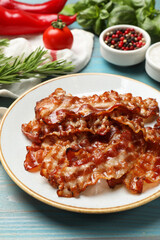 Slices of tasty fried bacon and different spices on light blue wooden table