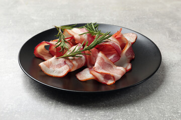 Slices of raw bacon and rosemary on light grey table