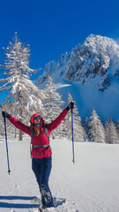 Woman walking in snow shoes with panoramic view of snow capped mountain peak Bielschitza in Karawanks, Bärental, Carinthia, Austria. Ski touring in winter wonderland in the Austrian Alps on sunny day