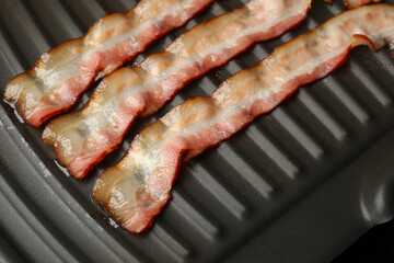 Slices of bacon on grill, closeup view