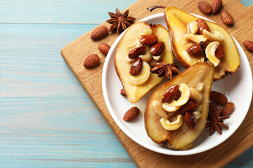 Delicious baked pears with nuts, anise stars and honey on light blue wooden table, top view. Space for text