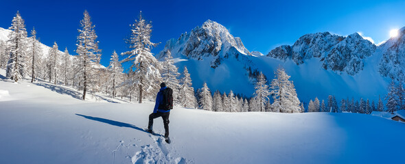 Man walking in snow shoes with panoramic view of snow capped mountain peak Bielschitza in...