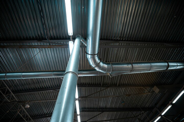 Detailed view of industrial ceiling with metal ducts and bright fluorescent lights, highlighting...