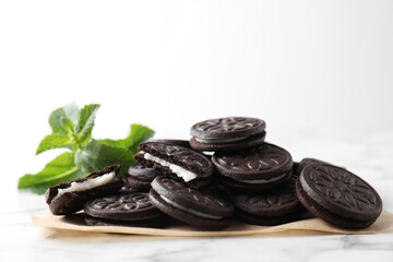 Tasty sandwich cookies and mint on white marble table