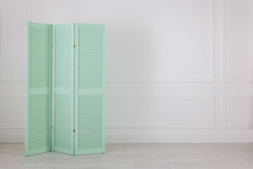 One folding screen near white wall indoors, space for text. Interior element