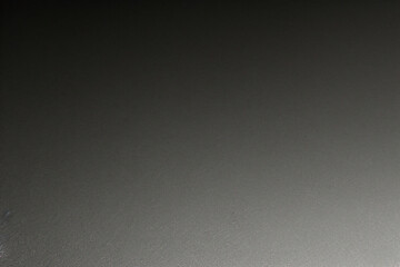 Black background made of real, shiny black paper covered with foil, illuminated by a soft light from above.