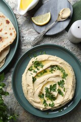 Delicious hummus with olive oil served on grey textured table, flat lay