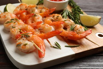 Skewers with delicious grilled shrimps served on wooden table, closeup