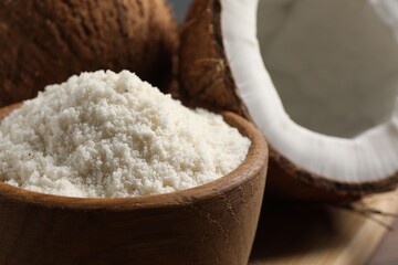 Coconut flour in bowl and fresh fruits on table, closeup