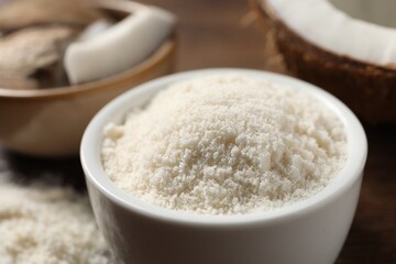 Organic coconut flour in bowl on table, closeup