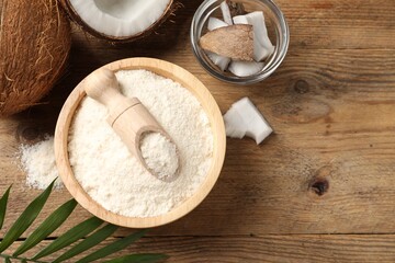 Coconut flour in bowl, scoop and fresh fruits on wooden table, flat lay. Space for text