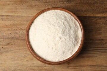 Coconut flour in bowl on wooden table, top view