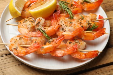 Skewers with delicious grilled shrimps served on wooden table, closeup