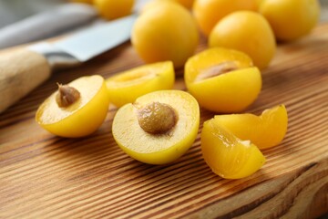 Whole and cut ripe plums on wooden table, closeup