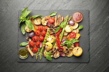 Delicious grilled vegetables and spices on grey textured table, top view