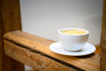 White cup with coffee on a saucer stands on a half-timbered beam