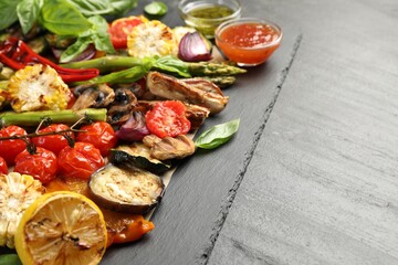 Delicious grilled vegetables served on grey textured table, closeup. Space for text