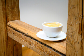 Coffee in a white cup and saucer stands on half-timbered beams in the serving hatch of an old German half-timbered house
