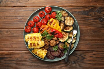 Delicious grilled vegetables and fork on wooden table, top view