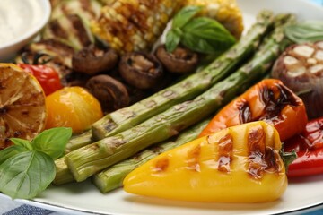 Delicious grilled vegetables with basil on table, closeup