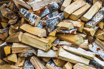 Close up view of large pile of dry birch firewood in backyard of villa.