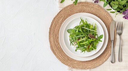 Flat lay of a fresh green salad with mixed leaves on a white plate and woven placemat, perfect for healthy eating, food photography, and minimalist dining concepts with copyspace.

