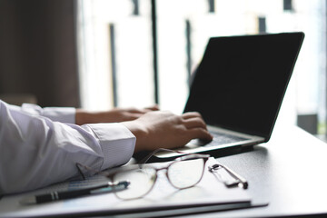 An asian young man accounting manager working at office table, checking the details of the graph and charts of the company total investment before submitting that paper documents to the boss.