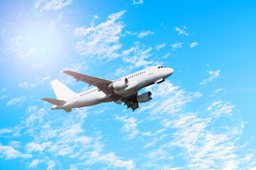 Flying airplane. Travel background with white commercial airplane flying in the blue sky