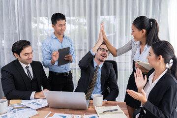 Group of happy businesspeople in high five gesture and successful efficient teamwork. Diverse race office worker celebrate after made progress on marketing planning in corporate office. Meticulous