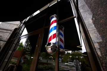 Barber shop exterior with vintage pole reflecting in glass during late afternoon