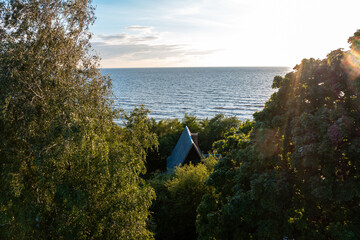 Rustic wooden cabin nestled in dense forest with a picturesque view of the open sea