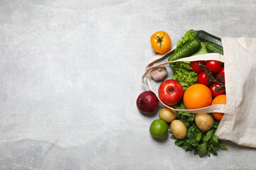 Vegan food delivery. Bag with different fresh vegetables and fruits on grey textured table, flat lay. Space for text